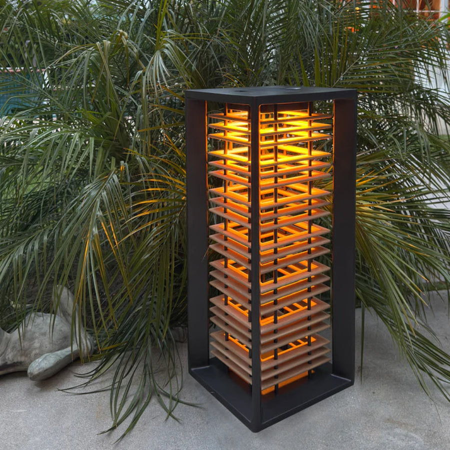 Decorative outdoor solar lamp with glowing interior, surrounded by green plants by Les Jardins available at Spacio retail stores in Mumbai & Kolkata.  