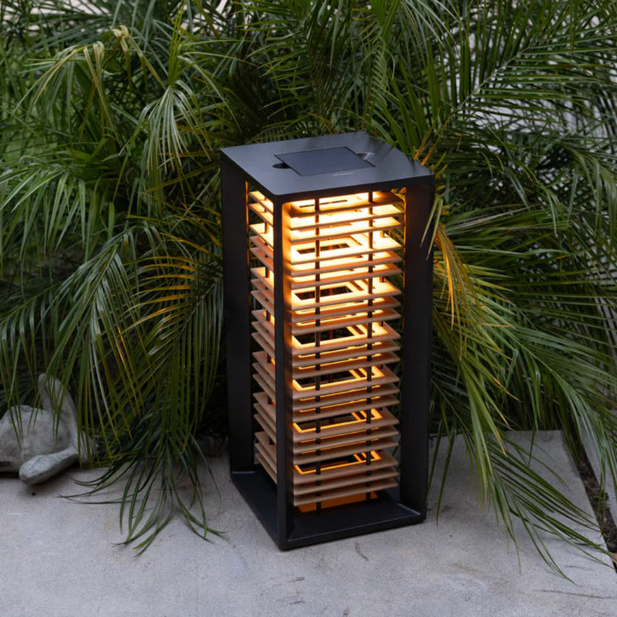 Outdoor solar lantern with glowing light surrounded by green foliage by Les Jardins available at Spacio retail stores in Mumbai & Kolkata.  