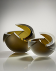 Two sculptural glass bowls with a reflective gold and silver finish, displayed on a reflective surface against a clean gray studio background.