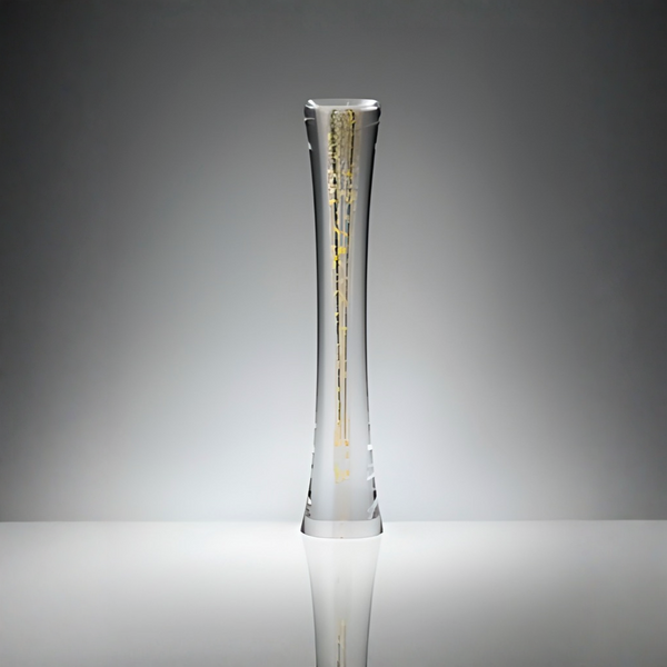 A tall, slender clear sculptural glass vase with a flared base, decorated with vertical gold leaf patterns, set against a gradient gray studio background.