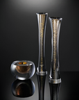 Three elegant glass vases with a smoky gray tint and embedded gold glitter, displayed on a reflective black surface against a dark gray gradient background.