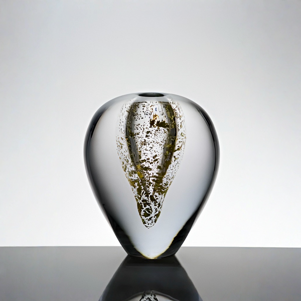 A sculptural glass vase with a teardrop silhouette and a textured, gold-toned abstract pattern inside, set against a light gray gradient background on a reflective dark surface.