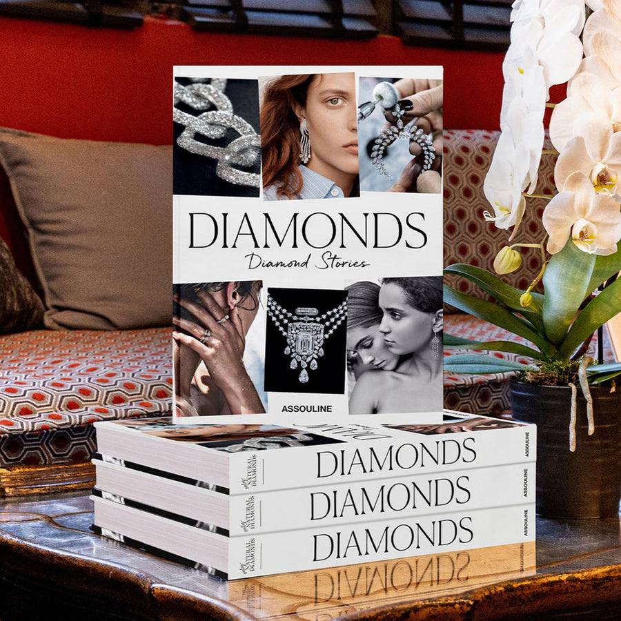 Assouline Diamonds: Diamonds Stories coffee table book on a wood coffe table beside a flower vase in modern interior available at Spacio India for luxury home decor collection of Jewellery Coffee Table Books.