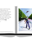 Assouline Louis Vuitton: Virgil Abloh Classic Cartoon Cover coffee table book displaying photo of Virgil Abloh flying a paper plane & quote on a white back ground available at Spacio India for luxury home decor accessories collection of Fashion Coffee Table Books.