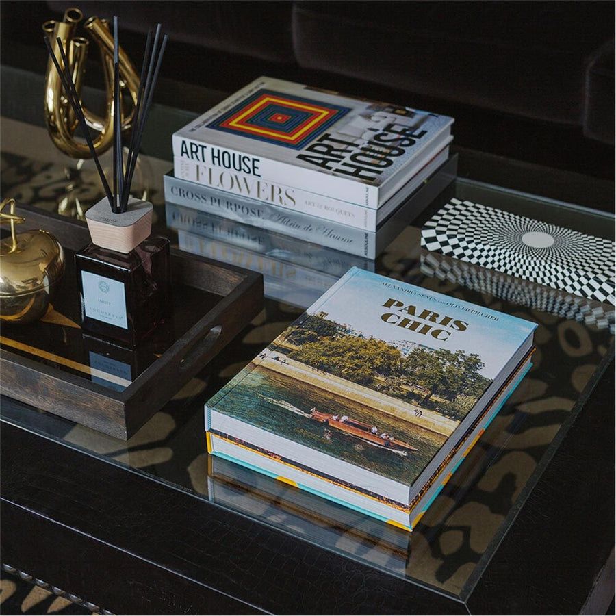 Assouline Paris Chic coffee table book on a coffee table with decor accessories -  books & diffuser in cozy interior table decor ground available at Spacio India for luxury home decor accessories collection of Travel Coffee Table Books.