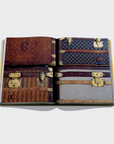 An open book or magazine spread showing multiple vintage-style Louis Vuitton luggage illustrations or photographs on the pages, photographed against a light gray background.