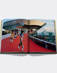 Open book showing a photograph of people on a red carpet with a modern building in the background