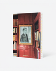 A hardcover book titled 'London Chic' featuring a red library interior cover with a framed portrait of a man, shown on a clean white background.