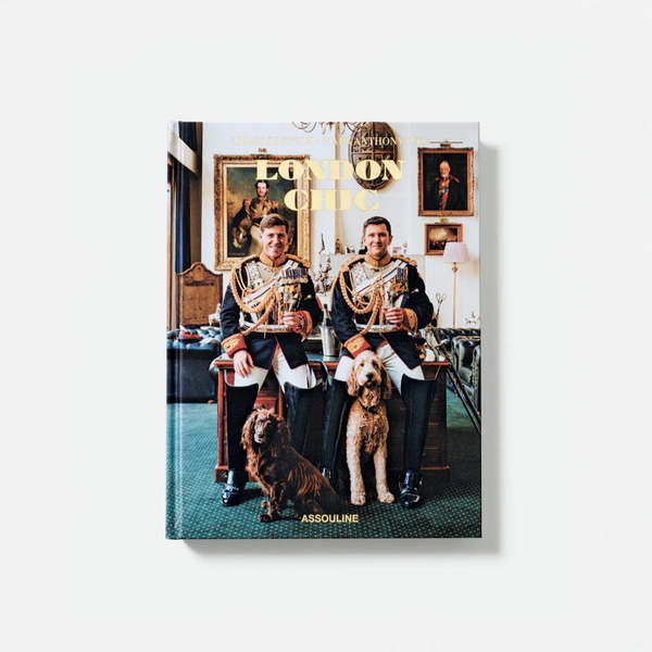 A hardcover book titled 'London Chic' by Charles Foster Assouline, featuring a cover photograph of two men in military dress uniforms sitting in a London cab with dogs, shown against a light gray background.