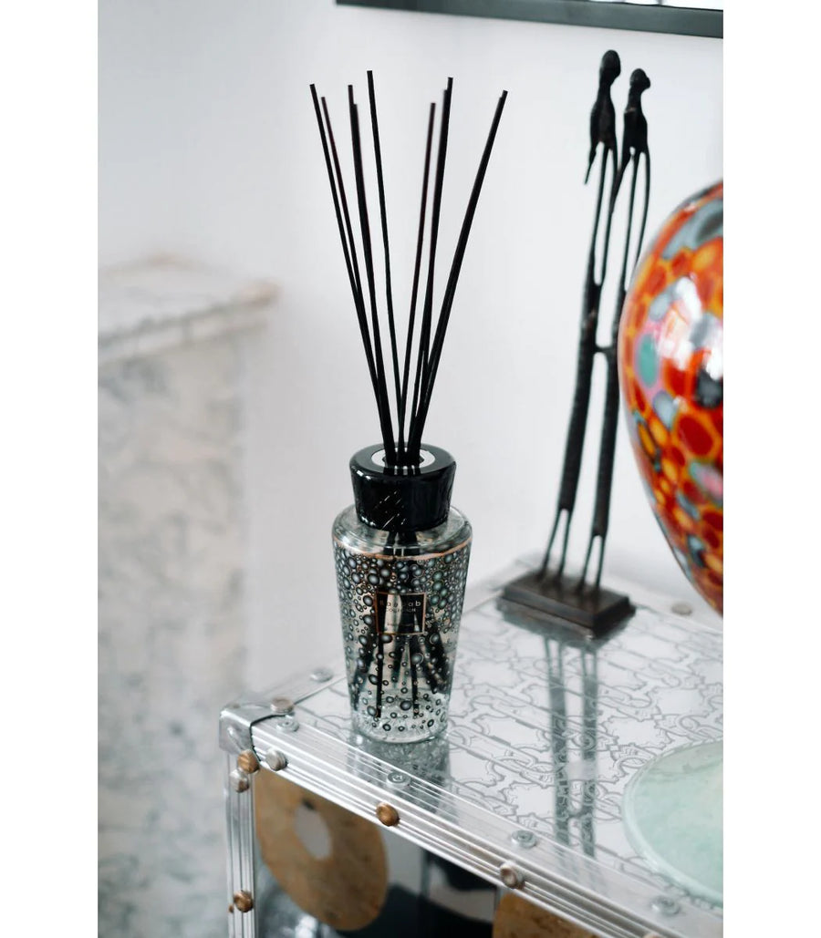 Baobab Black Pearls diffuser in a glass vase on a table.