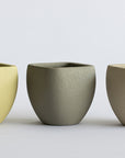 Three FRP planters pots in different colors on a light gray background