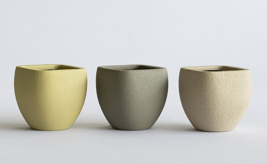 Three FRP planters pots in different colors on a light gray background