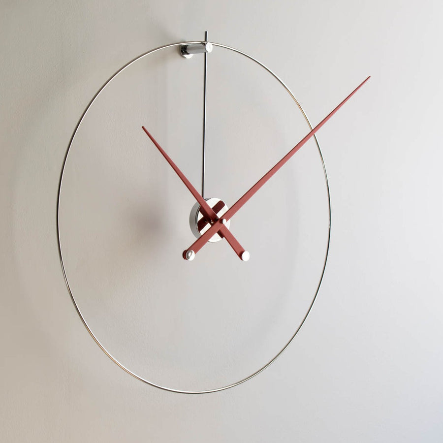 A Nomon minimalist wall clock with a red clock face.