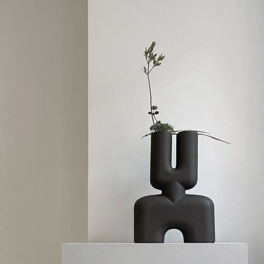 A 101 Copenhagen hand glazed vase with a quirky plant on top, perfect for an interior setting.
