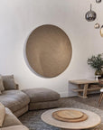 Modern living room with a round textured wall art piece by Gardeco, gray sofa, and wooden coffee table -  all available at Spacio retail stores in Mumbai & Kolkata.  