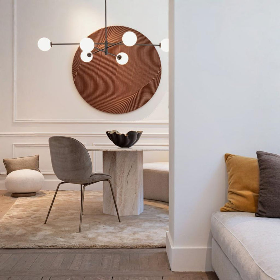 Modern interior design with a gray chair, beige sofa and a round wooden wall art piece by Gardeco available at Spacio retail stores in Mumbai & Kolkata.  