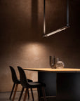 A high-end dining room with a black table and chairs featuring Esperia Eredania Horizontal Suspension Light for decorative lighting.