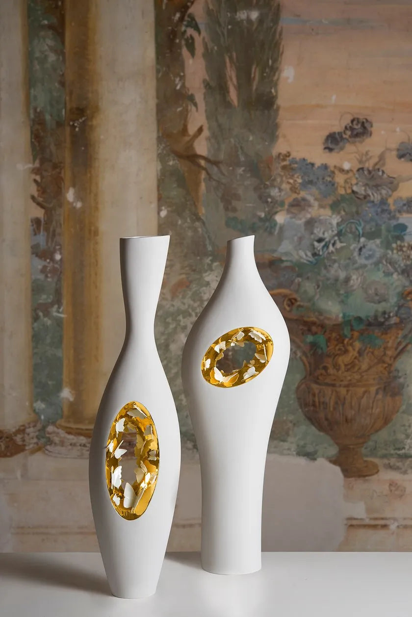 Two white and gold Fos Ceramiche Falling in Love Gold Vase (Pair) on a table in front of a painting.