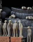 A group of people standing in front of a brick wall, featuring the Gardeco Ceramic Sculpture Visitor Small in Caqui finish.