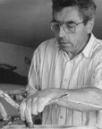 An old black and white photo of a man skillfully working on a piece of wood, creating intricate details with precision and expertise with the Gardeco Ceramic Sculpture Visitor Small Sand Cor02 from Gardeco.