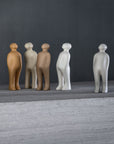 A collection of small Gardeco Ceramic Sculpture Visitor Small Caqui Cor21 figurines standing on a table, crafted by a talented Belgian sculptor with a stunning caqui finish.