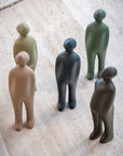 A group of Gardeco Ceramic Sculpture Visitor Small Caqui Cor21 figurines standing on a tile floor, sculpted by a Belgian artist.