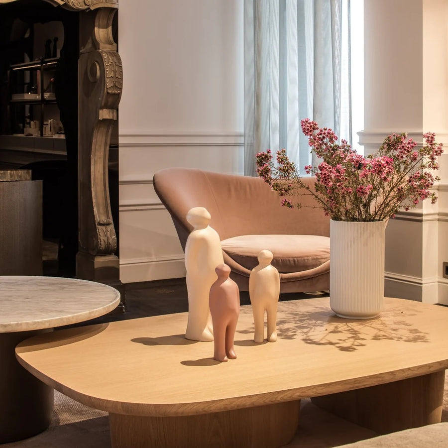 A meticulously crafted living room featuring a Gardeco Ceramic Sculpture Visitor Small Dune Cor47 coffee table adorned with a small figurine and a beautifully arranged vase of flowers, all showcased in an exquisite Dune finish.