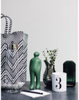 A Gardeco Ceramic Sculpture Visitor Small Green Alfafa Black Cor37 and a vase on a table with a black finish.