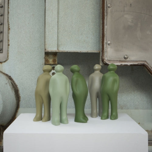 A group of small Gardeco Ceramic Sculpture Visitor Small Green Alfafa figurines standing in front of a Gardeco machine with a black finish.