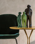 A table with a Gardeco Ceramic Sculpture Visitor Small Verde Cor52 chair and two small green figurines.