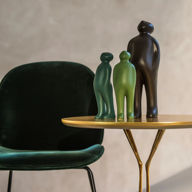 A table with a Gardeco Ceramic Sculpture Visitor Small Verde Cor52 chair and two small green figurines.