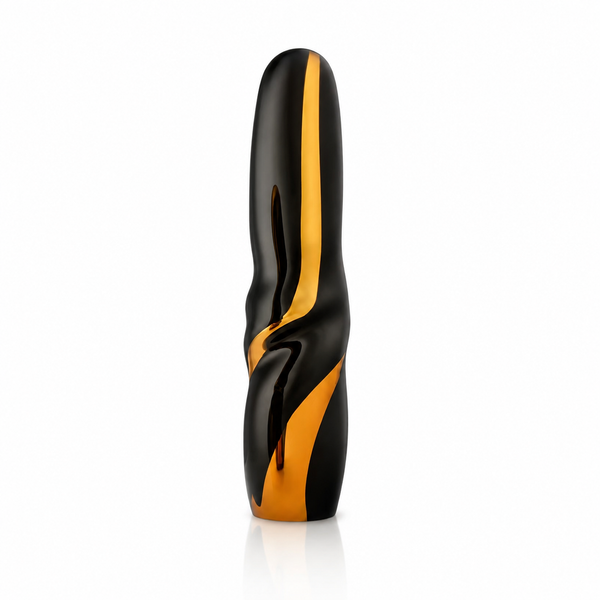 A modern, abstract-shaped glass sculpture with a glossy black finish and a prominent metallic gold accent stripe, standing upright on a white reflective surface by Glass Remis, available at Spacio in India. 
