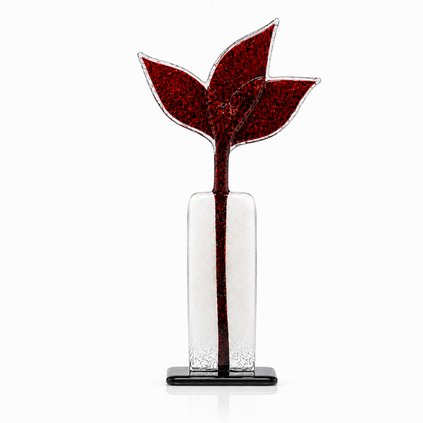 A decorative glass sculpture of a red flower with three leaves in a clear rectangular vase on a black base, photographed against a white background.