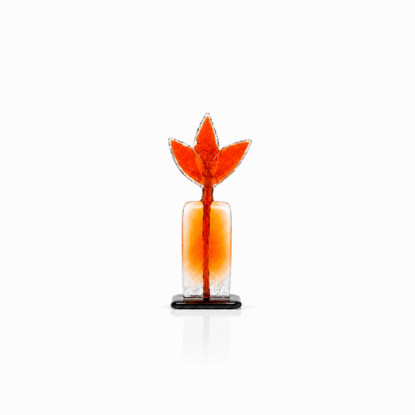 An orange and clear glass decorative sculpture with a stylized leaf or flame-shaped top and a small black base, centered on a white background.