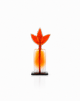 An orange and clear glass decorative sculpture with a stylized leaf or flame-shaped top and a small black base, centered on a white background.