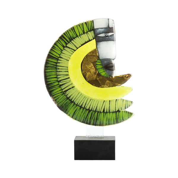 A modern abstract glass sculpture on a clear acrylic stand with a black base, featuring layered green and yellow crescent shapes with a stylized face on a white segment, set against a plain white background.