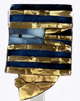 A closeup of a decorative glass sculpture of an abstract head in gold and blue colour on a white background. 