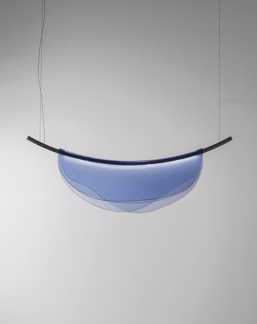 An Italamp Dali pendant light, embellished with a blue thermoformed glass shade, gracefully hangs from a ceiling.