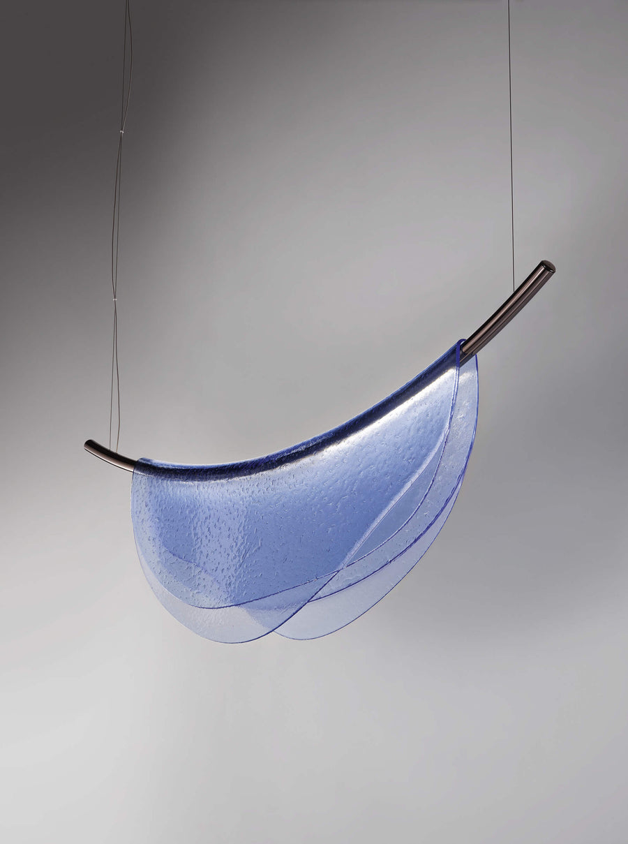 An Italamp Dali blue thermoformed glass pendant light hanging from a metal rod.
