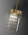 Modern pendant light with gold fixture and textured glass shade on a gray background