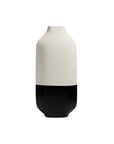 A minimalist ceramic vase with a matte off-white upper body and a glossy black lower base, centered on a plain white background.