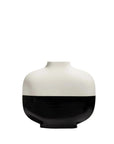 A minimalist ceramic vase with a glossy finish, featuring a two-tone design with a white upper half and a black lower half, centered on a solid white background.