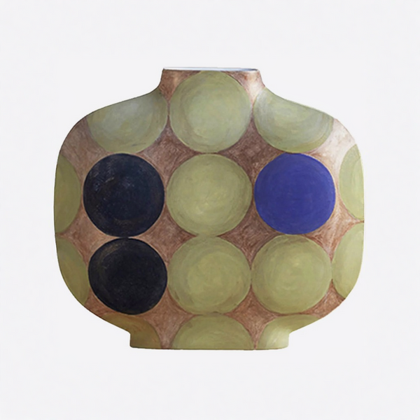 A ceramic vase with a rounded, bulbous shape featuring a pattern of overlapping circles in olive green, blue, and black on a warm brown background, set against a plain white studio backdrop.