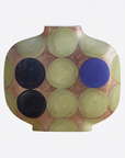 A ceramic vase with a rounded, bulbous shape featuring a pattern of overlapping circles in olive green, blue, and black on a warm brown background, set against a plain white studio backdrop.