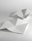Two abstract white geometric platters with folded, faceted surfaces displayed on a light gray studio background.