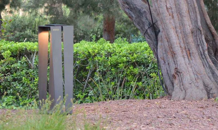 A Les Jardins Solar Lantern SKAAL Tink120 Small 500L Duratek post with a tree in the background, creating an outdoor oasis.