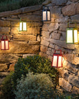 A group of Les Jardins outdoor solar lanterns hanging on a stone wall, providing portable and ambient lighting.