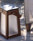 A Les Jardins LJ Solar Lantern Tinka Tink137 300L Muscade sitting on a wooden deck, emitting ambient lighting.