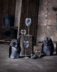 A set of owl-shaped decorative sculptures in various sizes, crafted from dark textured stone or metal, displayed on stands and pedestals in a rustic workshop setting.