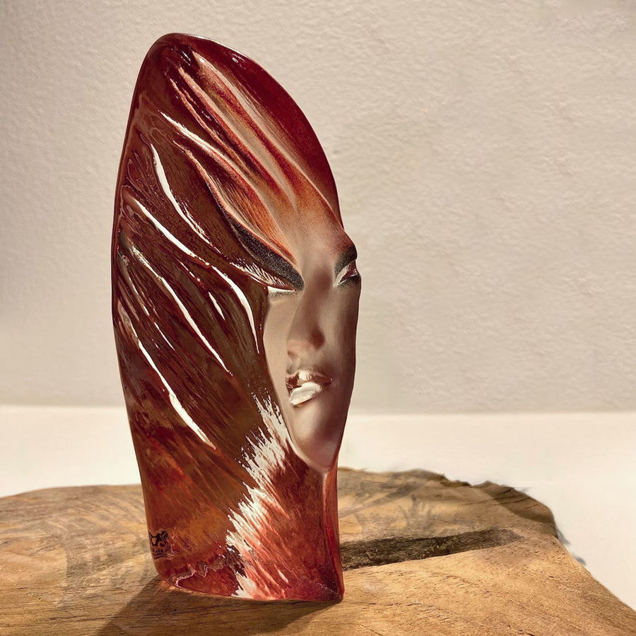 Side look of Maleras Crystal Noviata Red Sculpture on a wooden surface beside a flower vase in modern interior available at Spacio India from Sculpture and Art Objects Collection.